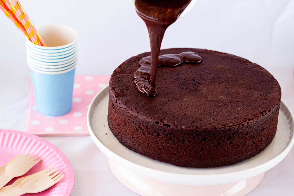 A Mars Bar ganache is being poured over a chocolate cake.